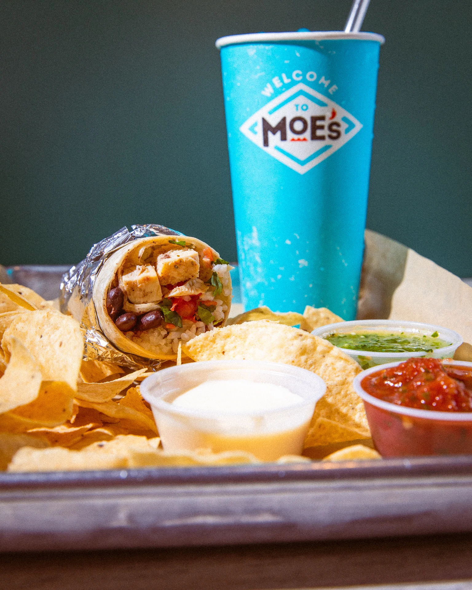 Moe's value meal with burrito, chips, and a drink on a tray